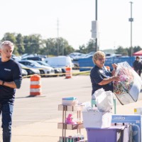 GVSU Alumni grabbing things from a pile and carrying it inside